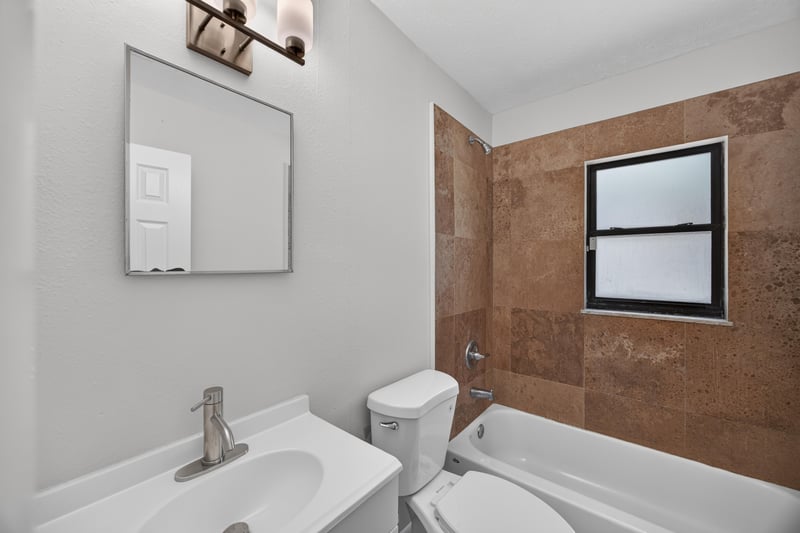 Bathroom with tub, tile surround and pedestal sink at 7453 Jade Dr N, Jacksonville, FL 32210