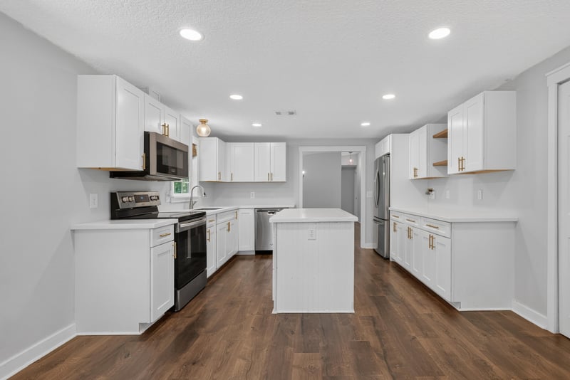 Kitchen with white cabinets, island, and wood floors at 4890 McAllister Rd, Middleburg, FL 32068