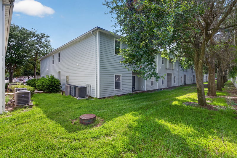Rear yard with trees and AC units at 7047 Deer Lodge Cir, Jacksonville