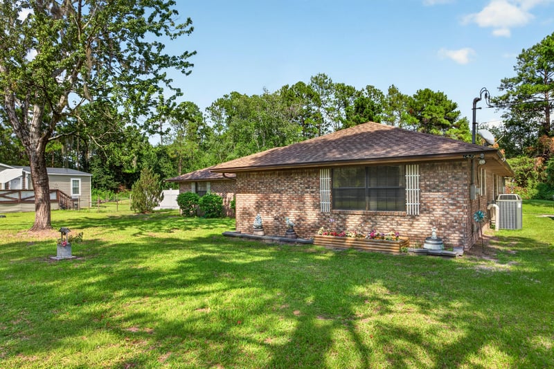 Side exterior view of the brick home and yard at 2435 Range Line Rd, Middleburg, FL
