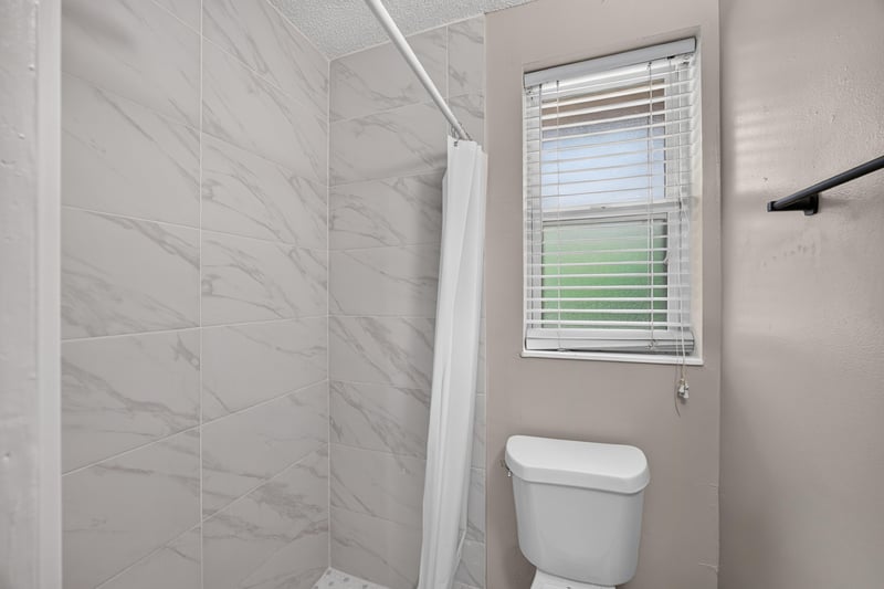 Bathroom shower with tile surround and toilet at 8067 Parental Cir, Jacksonville, FL 32216