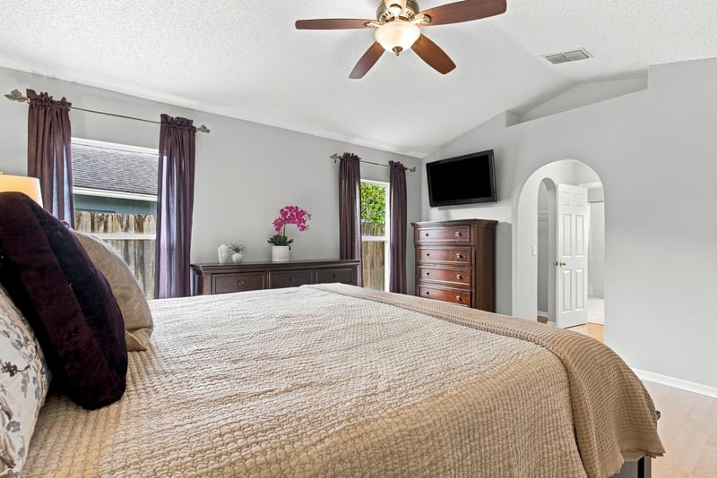 Primary bedroom with curtained windows and TV at 11197 Illford Dr