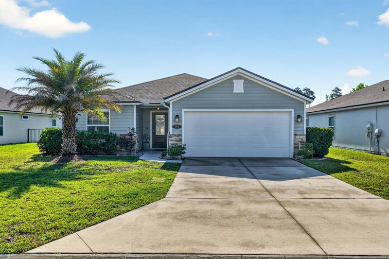 Front exterior at day-to-dusk with driveway and palm tree at 589 Seville Pkwy, St. Augustine, FL