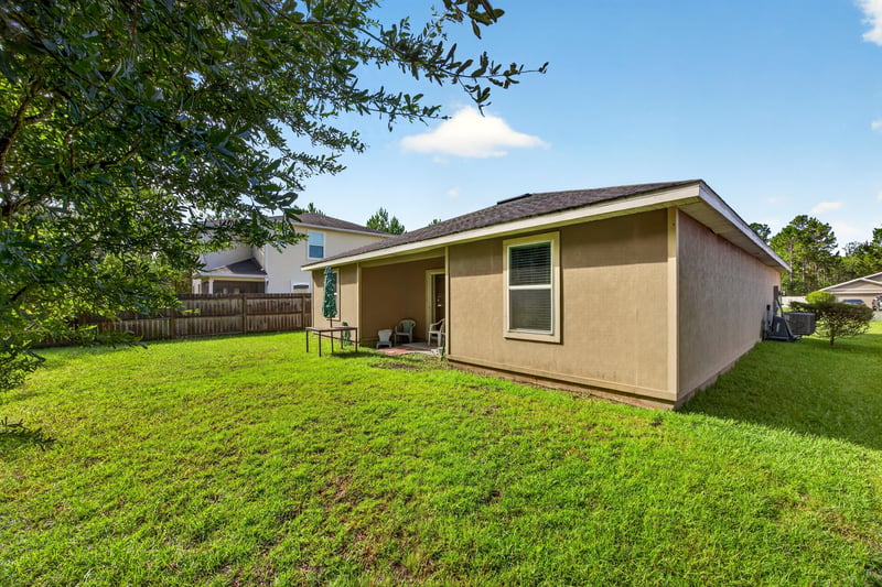 Backyard exterior view with young tree and fence at 518 Matecumbe Ct, Macclenny, FL