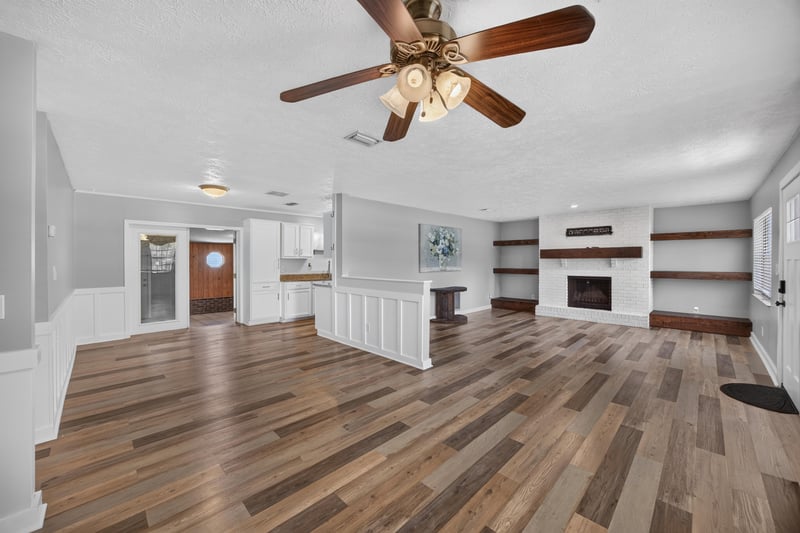 Open living area with ceiling fan and fireplace beyond at 6757 Deer Springs Rd, Keystone Heights, FL 32656