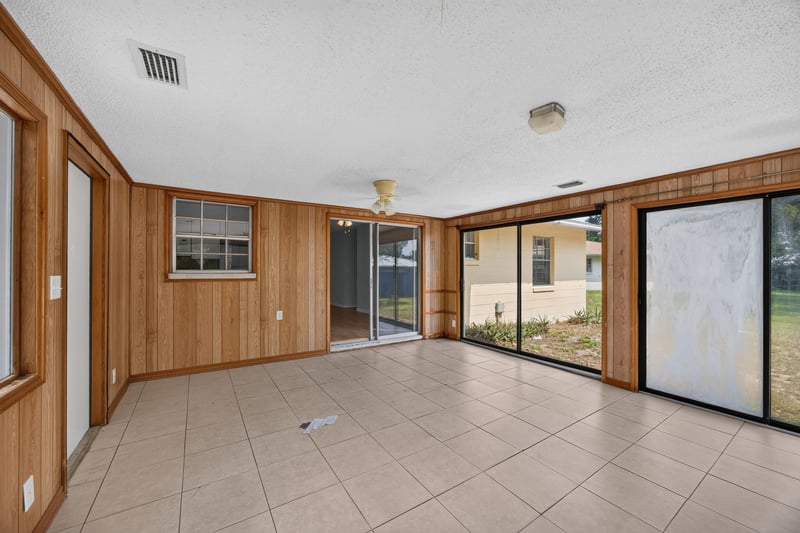 Sunroom with wood-paneled walls and sliding glass doors at 328 Palos Ct, St. Augustine, FL