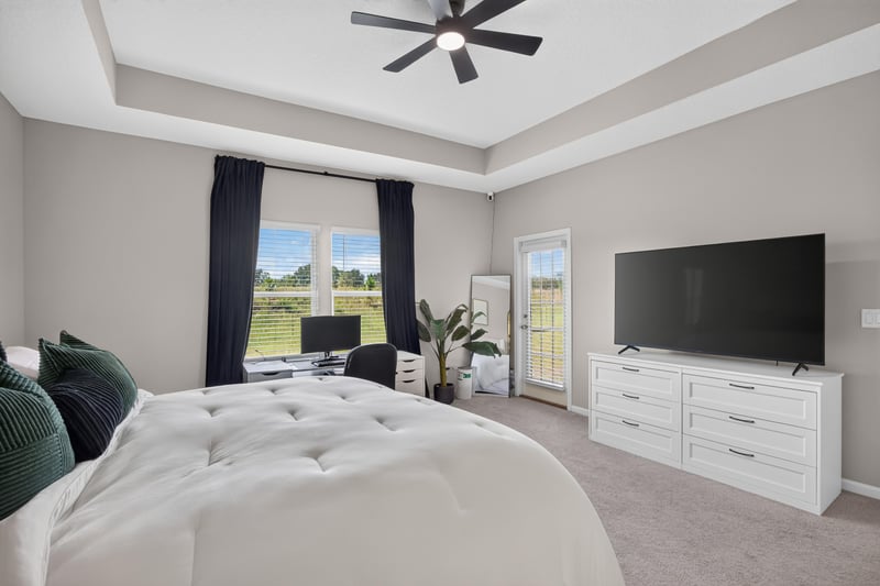 Primary bedroom with TV and ceiling fan at 9942 Lovage Ln, Jacksonville, FL 32219