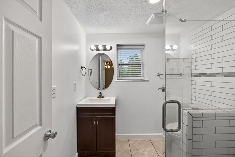 Bathroom with oval mirror vanity and glass shower at 1619 Hammond Blvd, Jacksonville, FL
