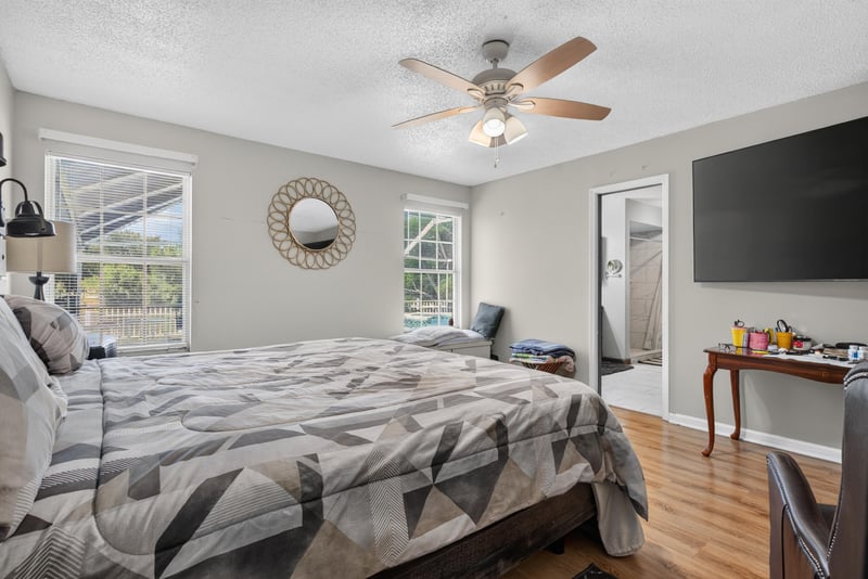 Bedroom with wall-mounted TV and mirror at 8680 Bandera Cir S, Jacksonville, FL 32244