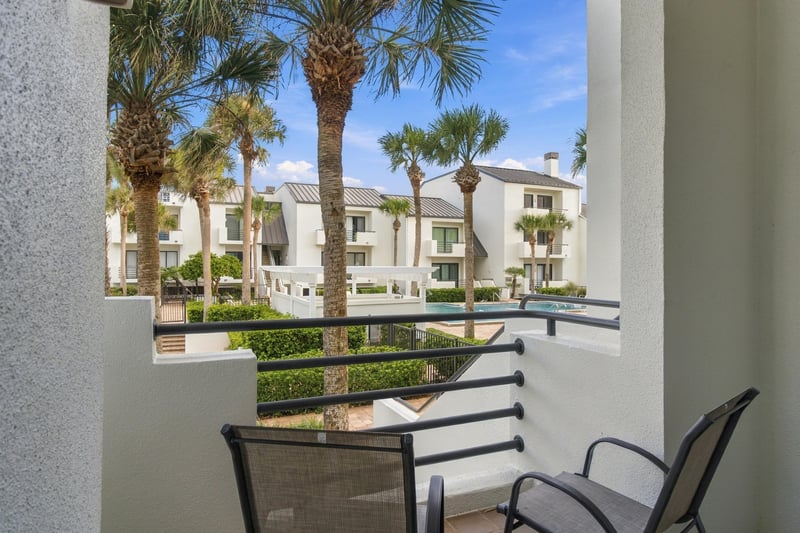 Balcony view of courtyard and pool through palm trees at 805 Spinnakers Reach Dr, Ponte Vedra Beach, FL 32082