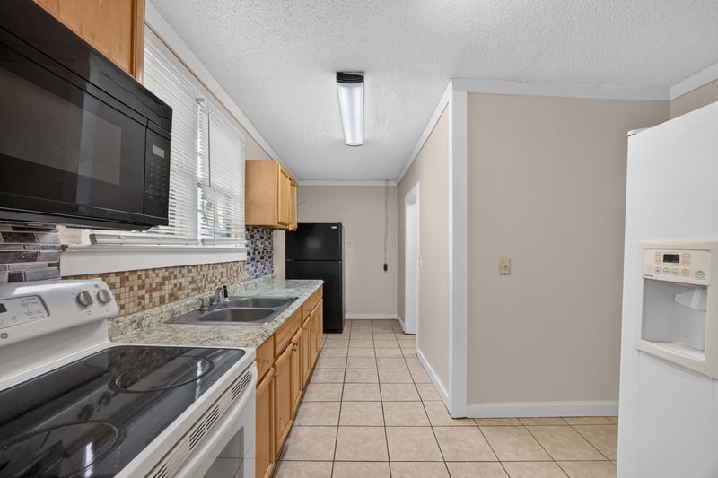 Kitchen view with black microwave and wood cabinets at 1473 State St W, Jacksonville, FL 32209