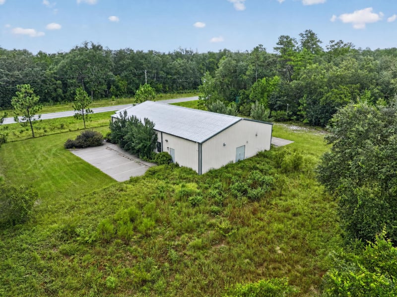 Drone aerial of the building and driveway from above the tree line at 1038 County Rd 315, Melrose
