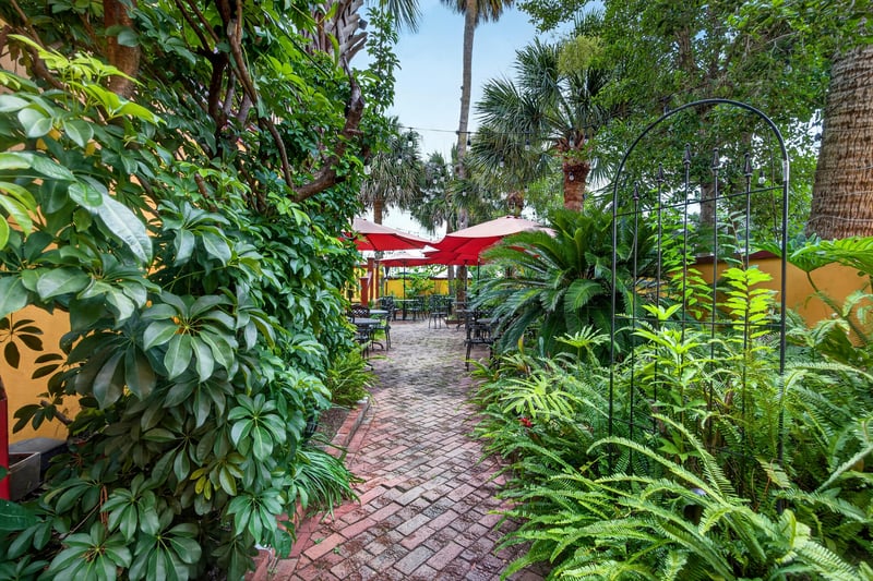 Courtyard brick path lined with tropical greenery at 115 Cordova St, St. Augustine, FL