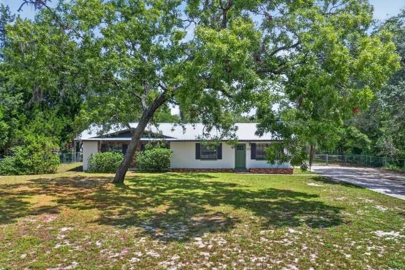 Front exterior with large oak tree and driveway at 6757 Deer Springs Rd, Keystone Heights, FL 32656