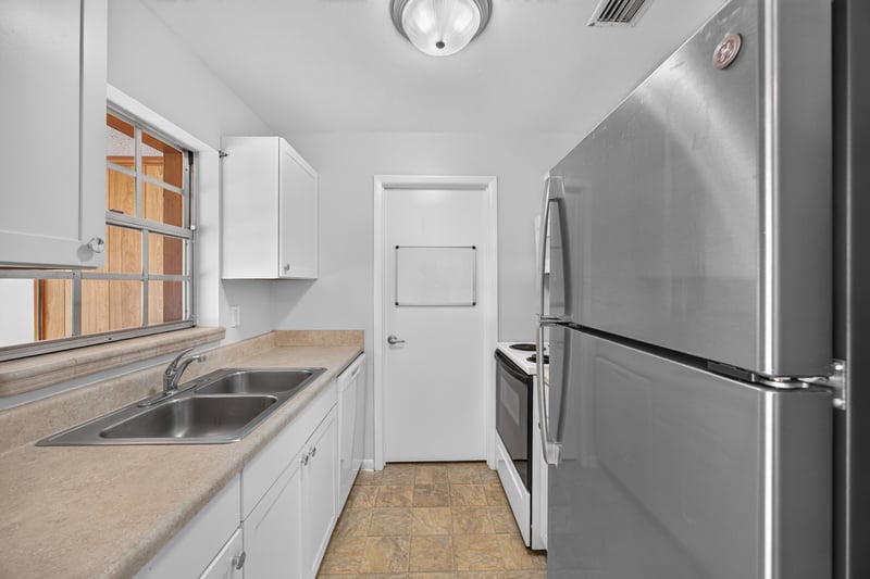 Kitchen with white cabinets, sink, and stainless refrigerator at 328 Palos Ct, St. Augustine, FL
