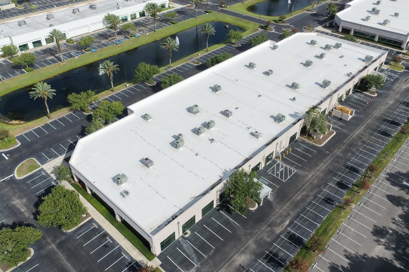 Aerial view of a roofline with pond and palm-lined parking at 10550 Deerwood Park Blvd, Jacksonville, FL 32256