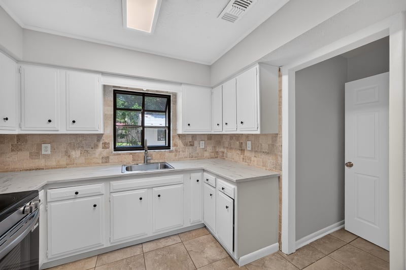 Kitchen corner view with white cabinets and tile floor at 7453 Jade Dr N, Jacksonville, FL 32210