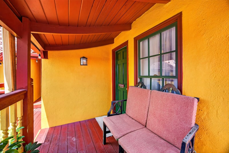 Covered porch with a pink loveseat and arched windows at 115 Cordova St, St. Augustine, FL