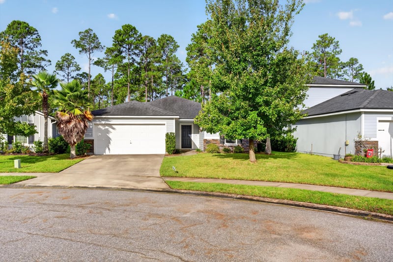 Front exterior with driveway and trees at 95221 Siena Ct, Fernandina Beach, FL 32034