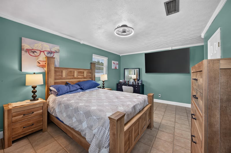 Primary bedroom with wood bed and wall-mounted TV at 6059 Karen St, Jacksonville, FL 32244