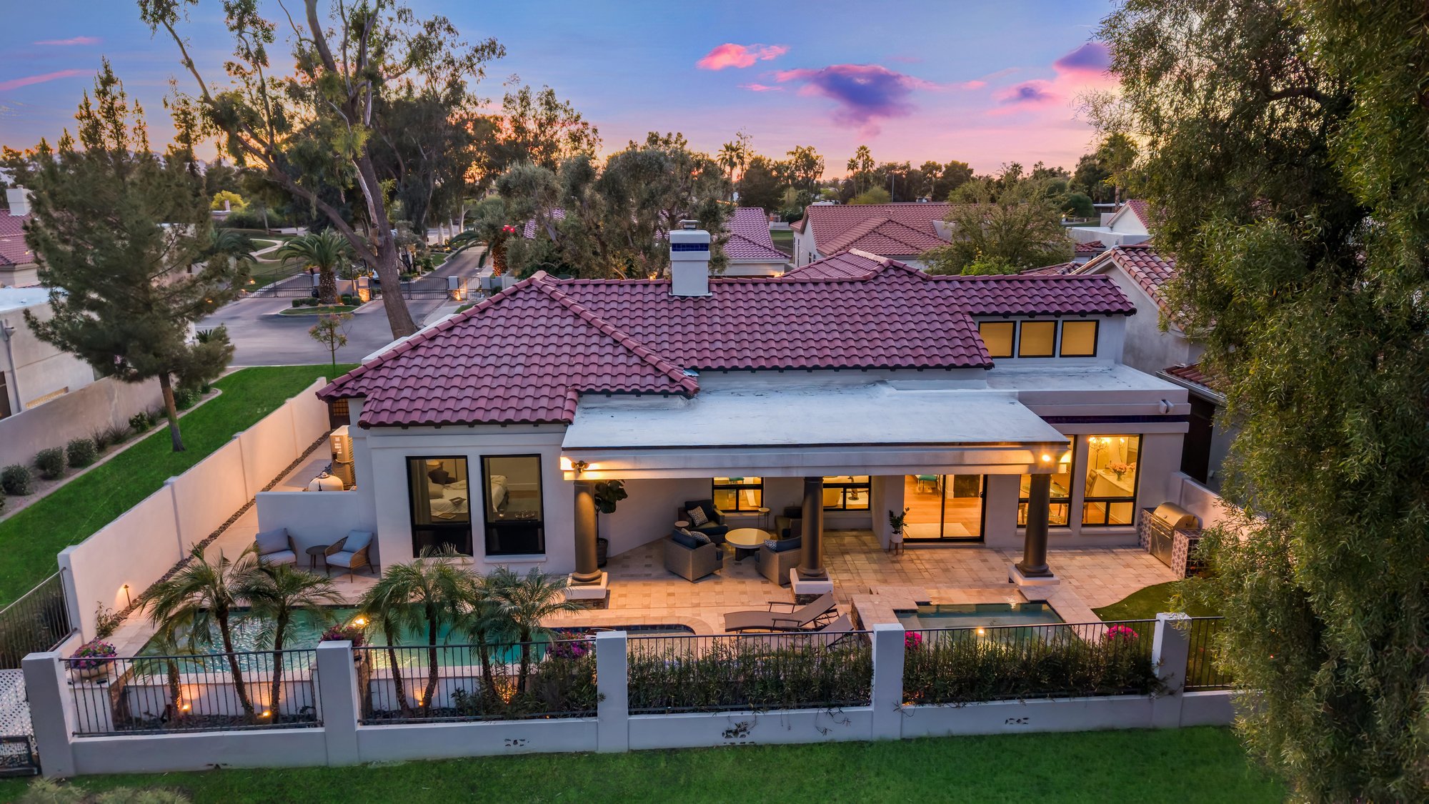 Aerial of a tile-roof home and backyard pool at dusk