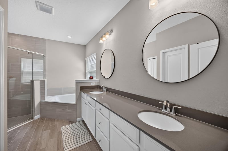 Primary bathroom with double vanity and round mirrors at 9942 Lovage Ln, Jacksonville, FL 32219