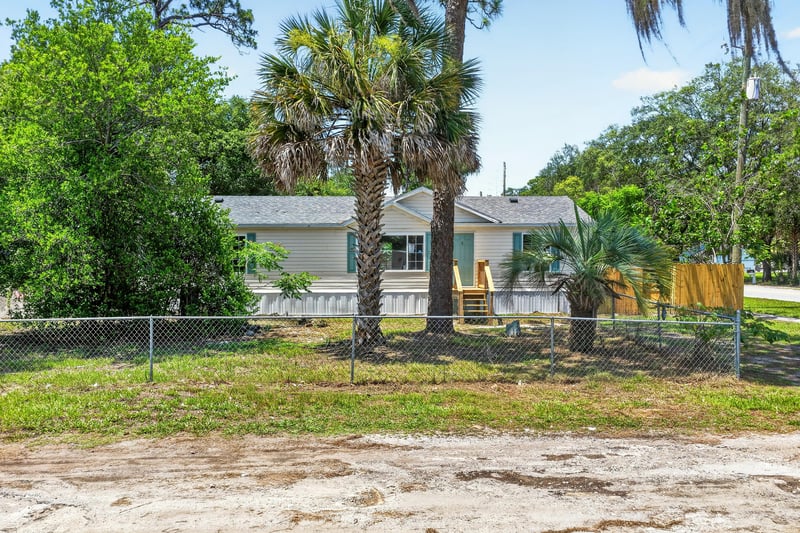 Front exterior view across chain-link fenced yard at 7603 Coach Park Dr, Jacksonville, FL 32244