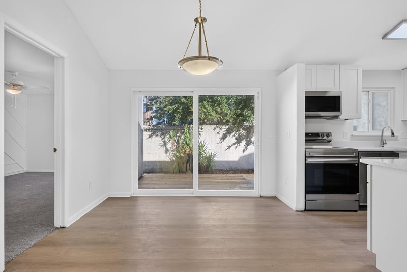 Dining area with sliding door and range, virtually staged at 8177 Virgo St, Jacksonville, FL 32216