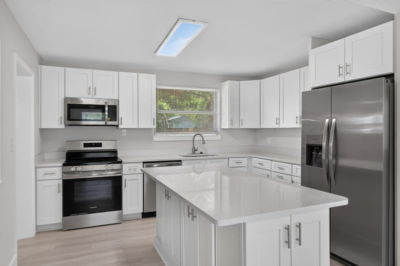 Kitchen with white cabinets, island, and skylight at 6238 Randia Dr, Jacksonville, FL 32210