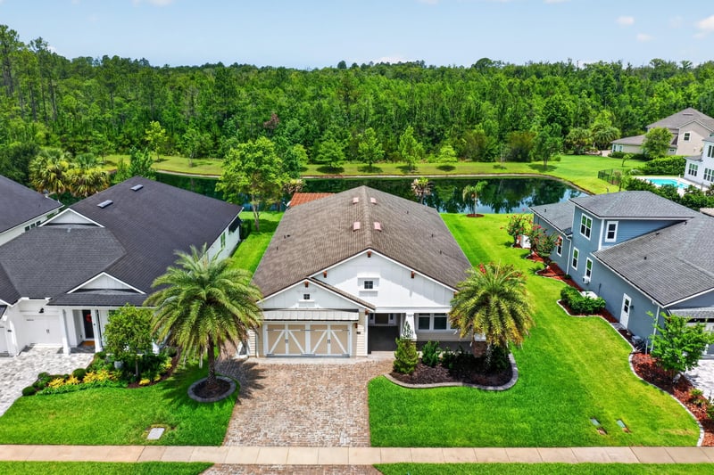 Aerial view of the home among neighboring houses and pond in St. Johns, FL