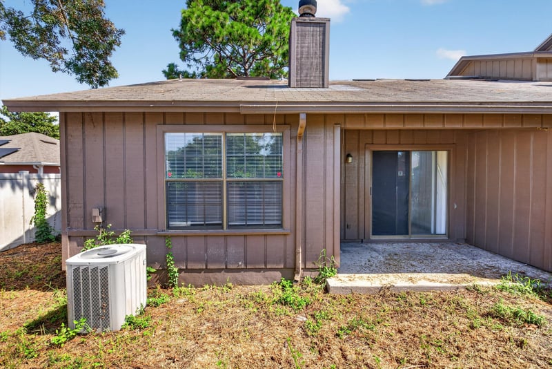 Back exterior with chimney and patio door at 8010 International Village Dr, Jacksonville, FL 32277