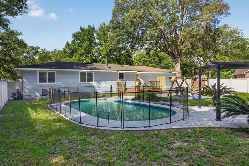 Front yard view with pool fence visible through trees at 892 Branscomb Rd, Green Cove Springs, FL