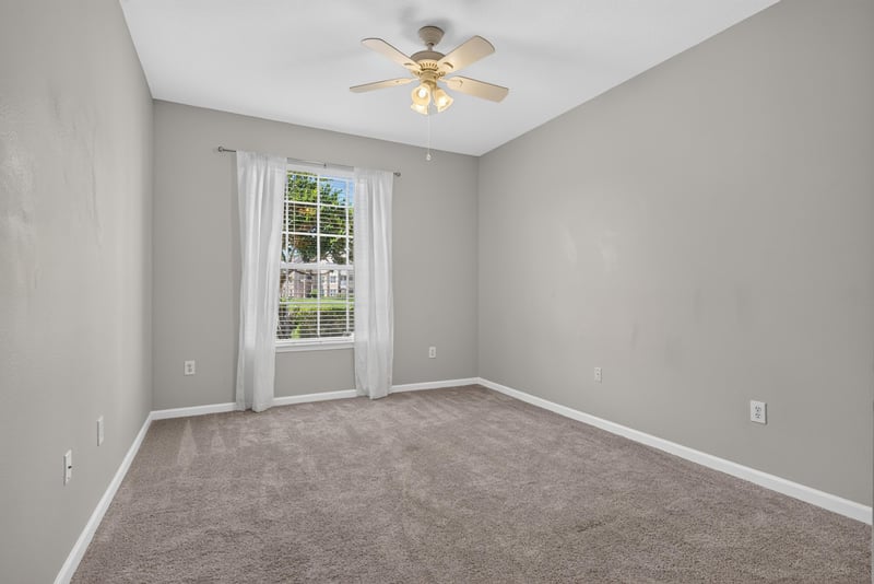Primary bedroom with window and carpet at 7990 Baymeadows Rd E #404, Jacksonville, FL 32256