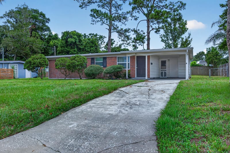 Front exterior with driveway leading to carport at 87 Saratoga Cir S, Atlantic Beach, FL