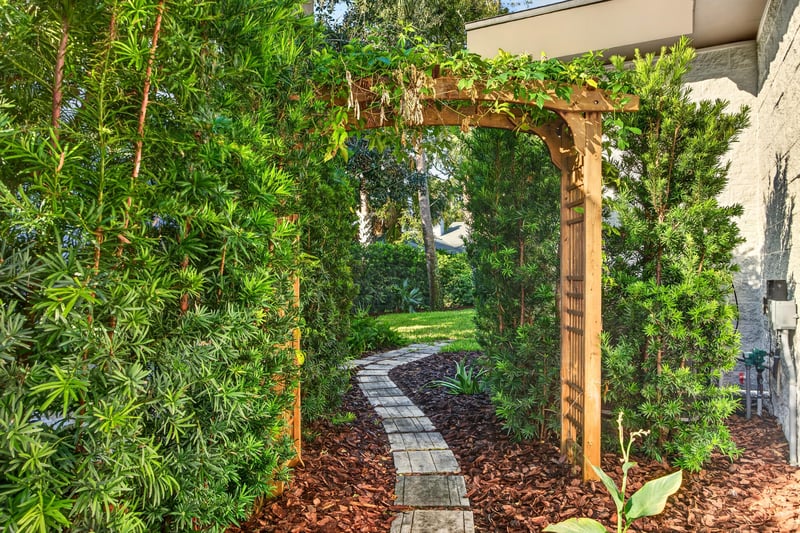 Side yard garden path with wood pergola and landscaping at 722 3rd Ave N, Jacksonville Beach, FL