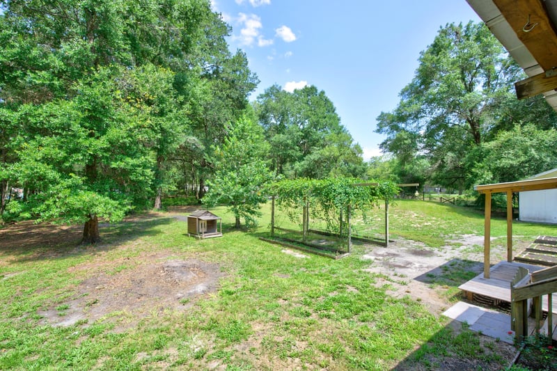 Side yard with covered porch and wooded lot at 2549 Snapdragon Ave, Middleburg, FL 32068