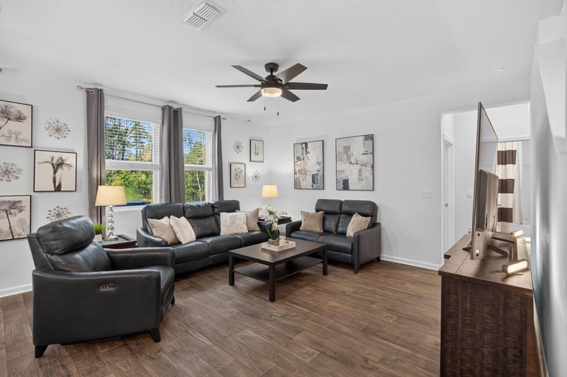 Living room with leather sofas and ceiling fan at 65255 Frst Glen Ln, Yulee, FL 32097