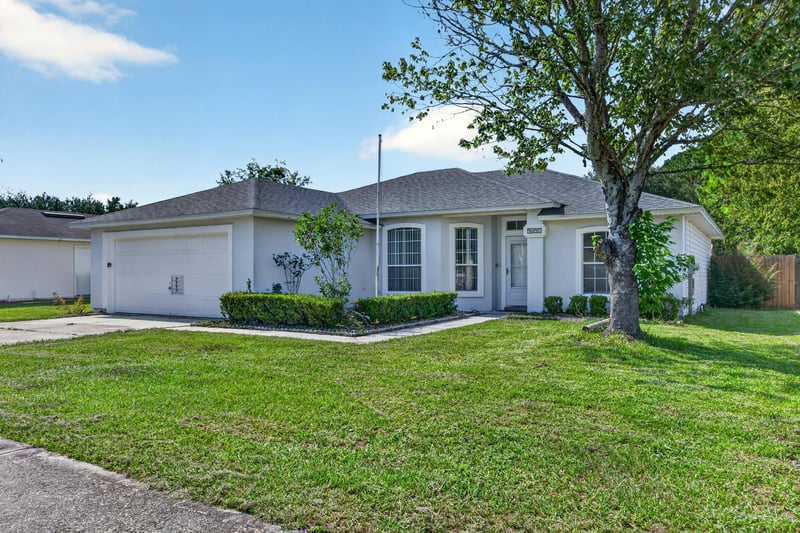 Front exterior with shrubs and mature trees at 9691 Nelson Forks Dr, Jacksonville, FL 32222