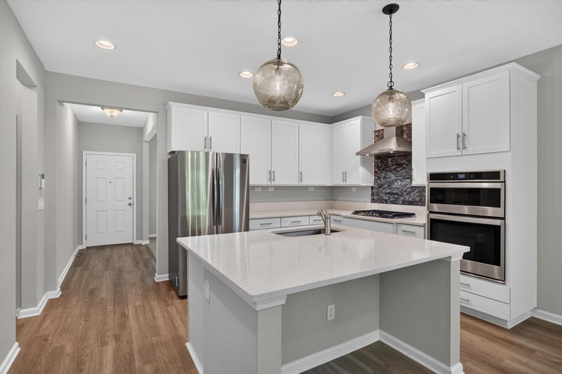 Kitchen island with white cabinets and pendant lights at 75875 Saffron Ln, Yulee, FL 32097