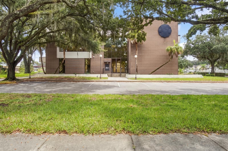 Front view of brick building with oak canopy and lawn at 101 Scholars Wy