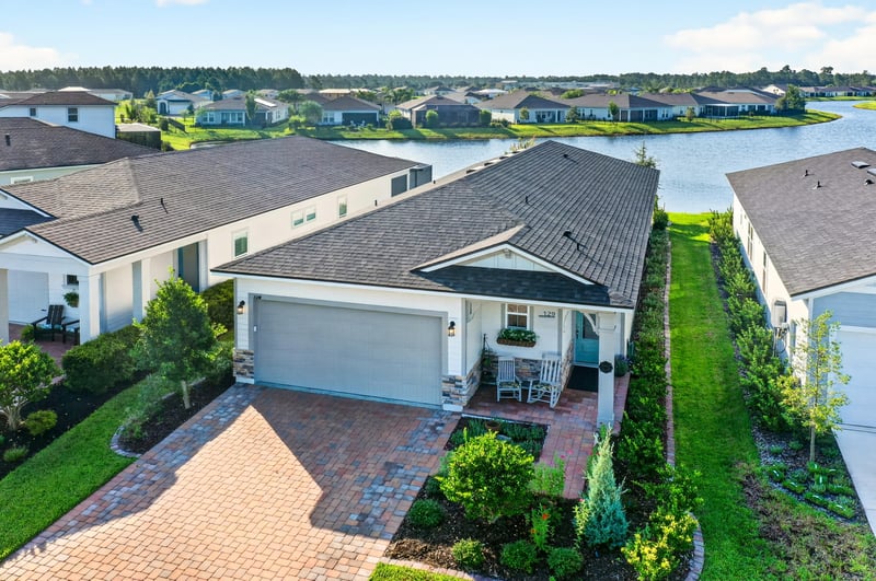 Day-to-dusk aerial of the home's roofline and pond view at 129 Amberwood Dr, St. Augustine, FL