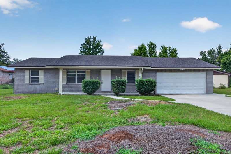 Front exterior view of gray brick ranch home with two-car garage at 1143 Tumbleweed Dr, Orange Park, FL 32065