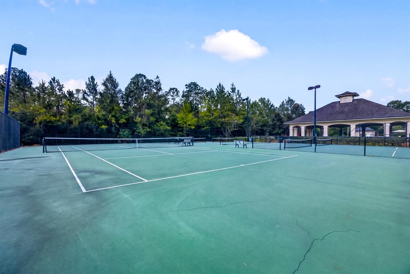 Tennis court with clubhouse in background in River Glen