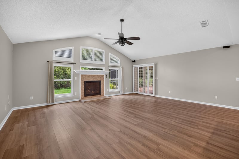 Empty living room with fireplace and tall windows at 1955 GUARDED Way, Fleming Island, FL 32003