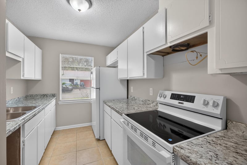 Kitchen with white cabinets and electric range at 1040 Willow Cove Ct E, Jacksonville, FL 32233
