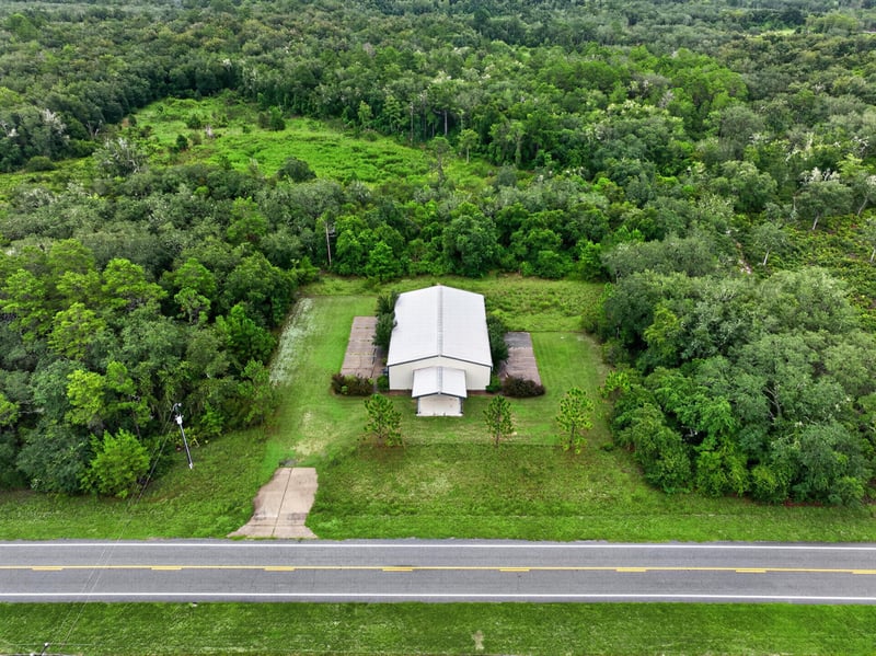 Drone aerial of the building across an open field at 1038 County Rd 315, Melrose