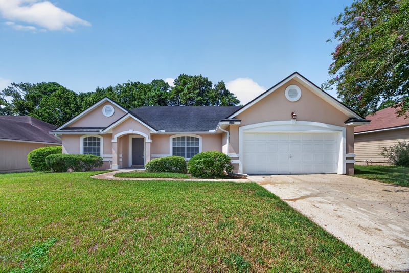 Front exterior with arched window and two-car garage at 9256 Dale View Ln W, Jacksonville, FL 32225