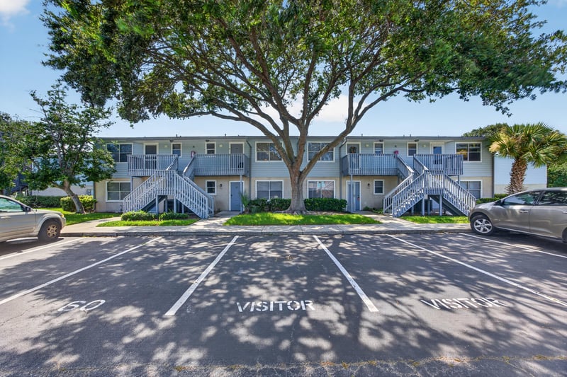 Front exterior of the two-story condo building with visitor parking at 700 W Pope Rd unit h61, St. Augustine, FL 32080