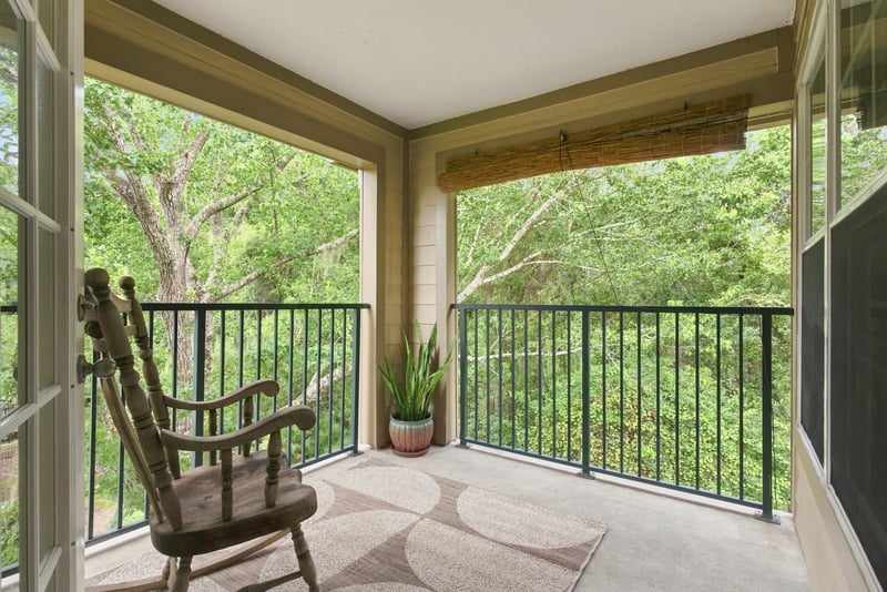 Screened porch with rocking chair and tree view at 7800 Point Meadows Dr, Jacksonville, FL 32256