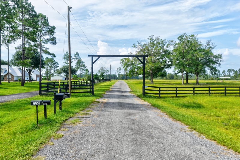Gravel driveway leading through a ranch-style entrance gate at 7500 Lucky Seven Rnch Rd, Macclenny, FL